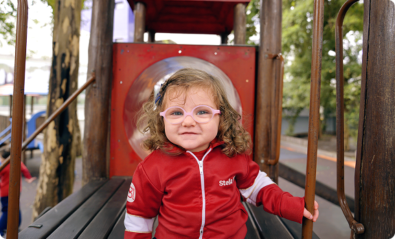 Criança do Colégio Stella Maris sorrindo em um playground